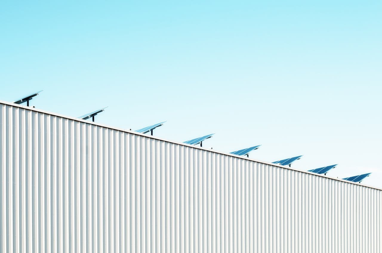 Corrugated steel building with solar panels under a clear blue sky, emphasizing sustainability.