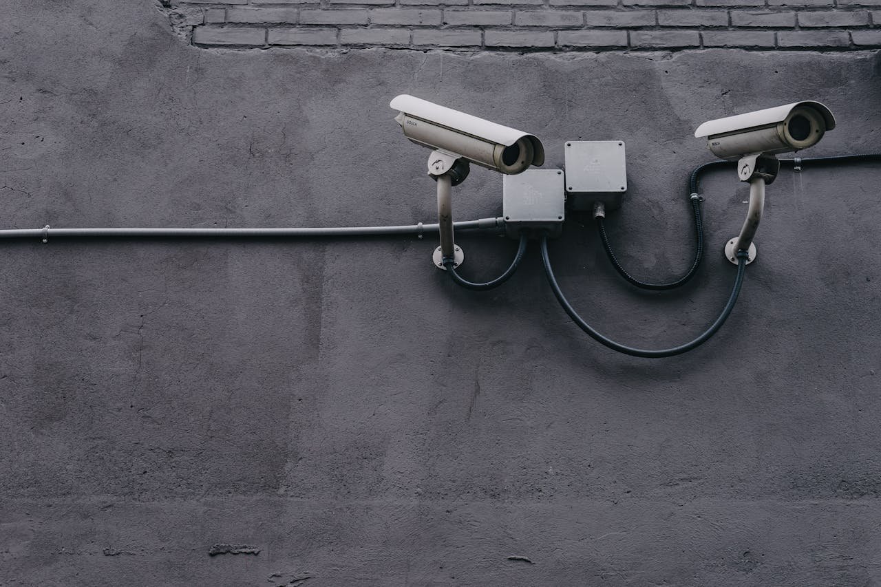 Two surveillance cameras mounted on a concrete wall, highlighting security technology.